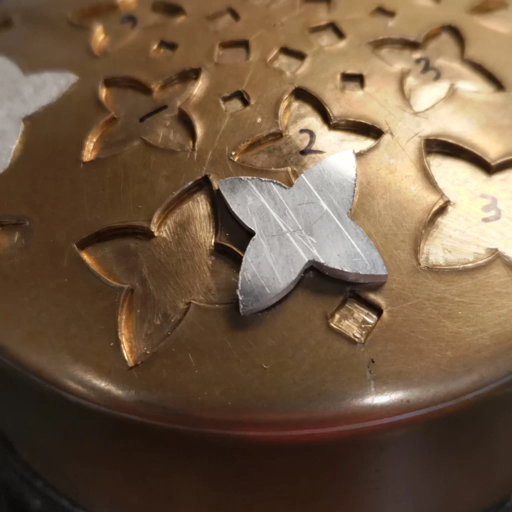 Primer plano de una pieza de laton con cincelado inicial del maestro orfebre Toru Nishiyama.