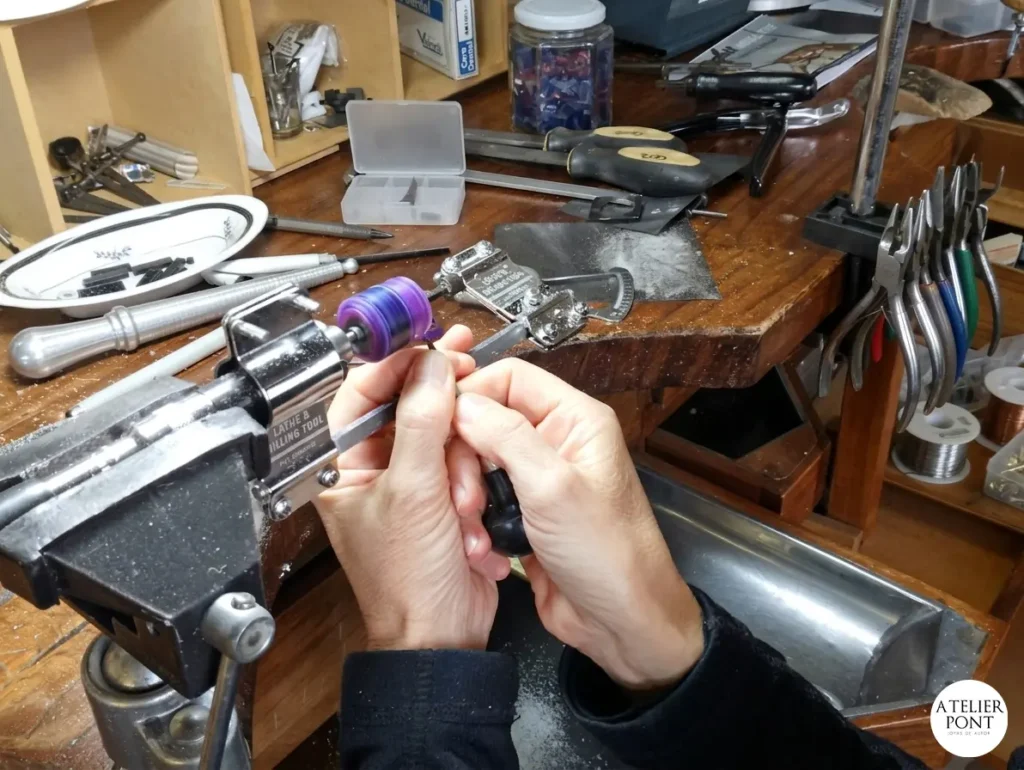 Artesana orfebre trabajando cera dura con torno en taller de joyería.