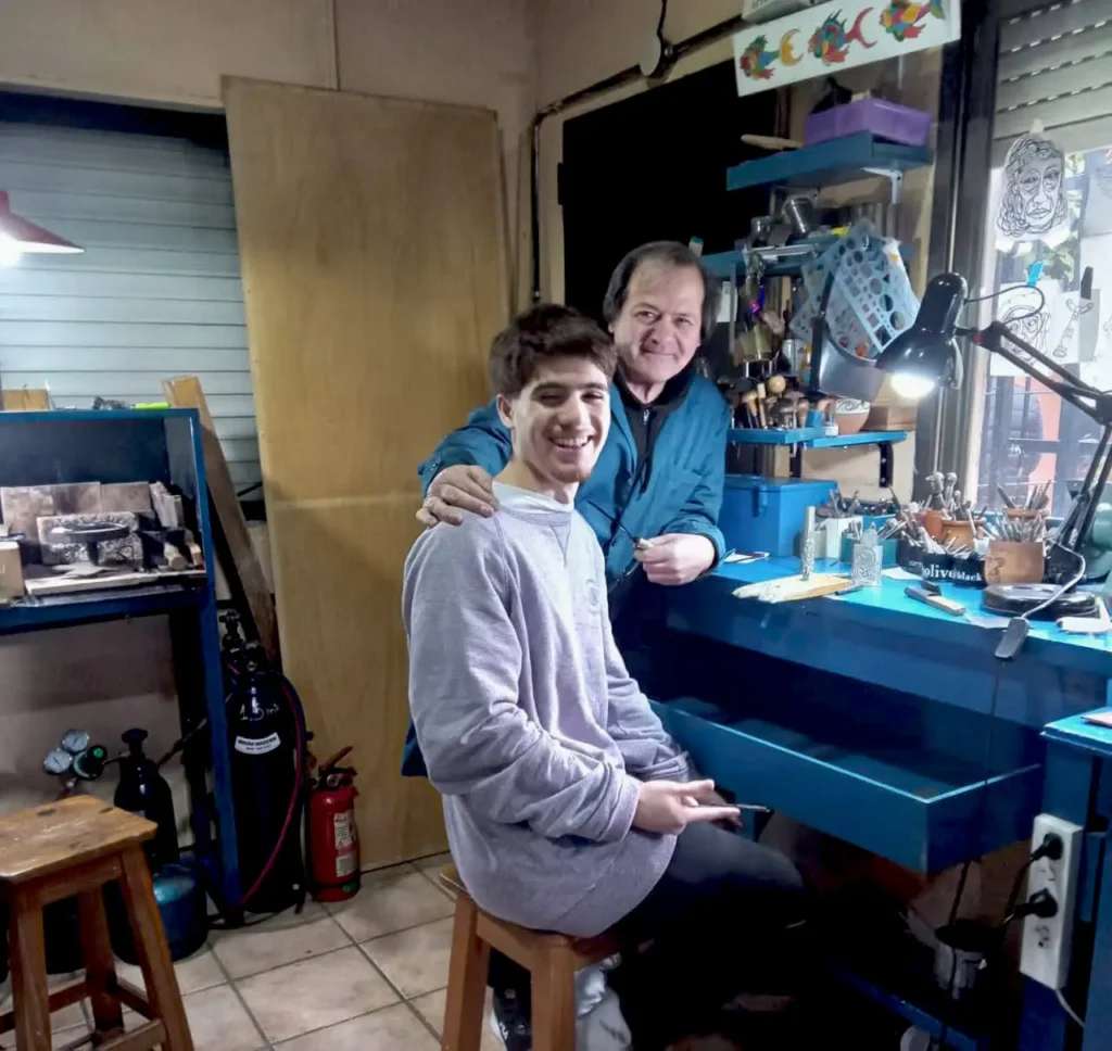 Los orfebres Dante Conti y su hijo Pablo trabajando juntos en su taller de platería.